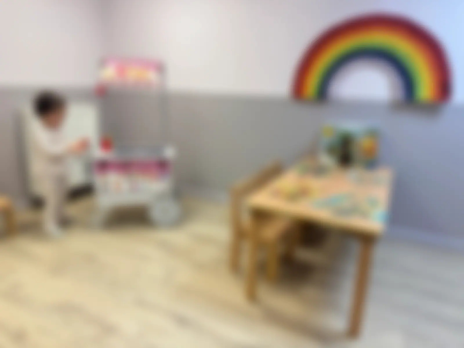 Free-flow play zone with role-play shop, rainbow wall art and small tables